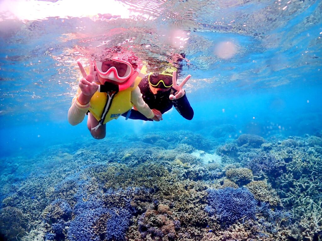 親子でサンゴ礁の海をシュノーケリングしている様子