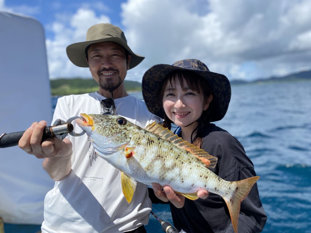 カップルが釣り上げた魚を2人で持っています。とても楽しそうです
