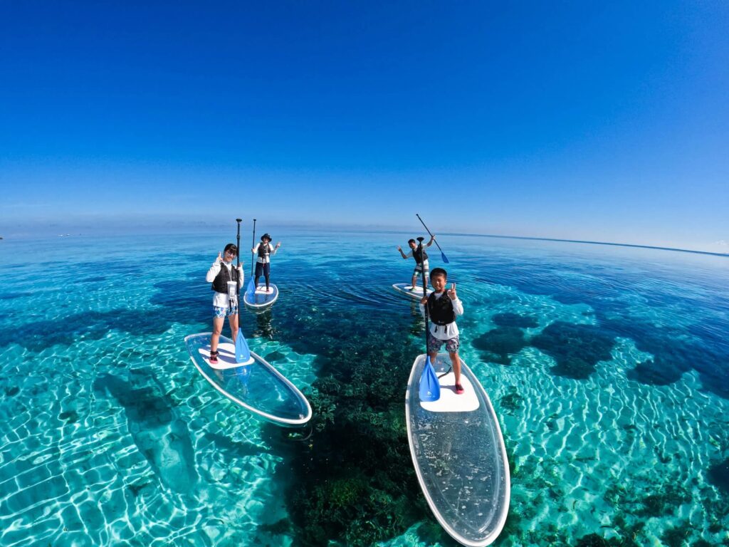 家族4人で透明度の高い海でSUPしている様子